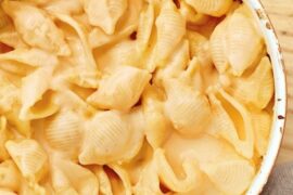 A plate of caracoquesos, shell-shaped pasta covered in a creamy melted cheese sauce.