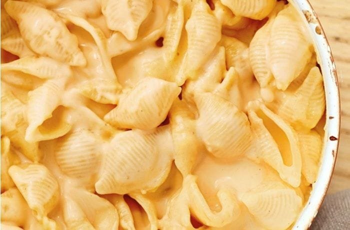 A plate of caracoquesos, shell-shaped pasta covered in a creamy melted cheese sauce.