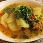 Chilean smoked longaniza soup with potatoes and noodles in a deep bowl