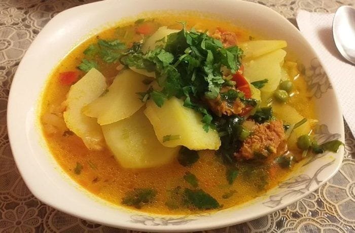 Chilean smoked longaniza soup with potatoes and noodles in a deep bowl