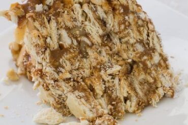 Slice of Chilean soda cracker cake layered with manjar and jam, a no-bake dessert dusted with powdered sugar
