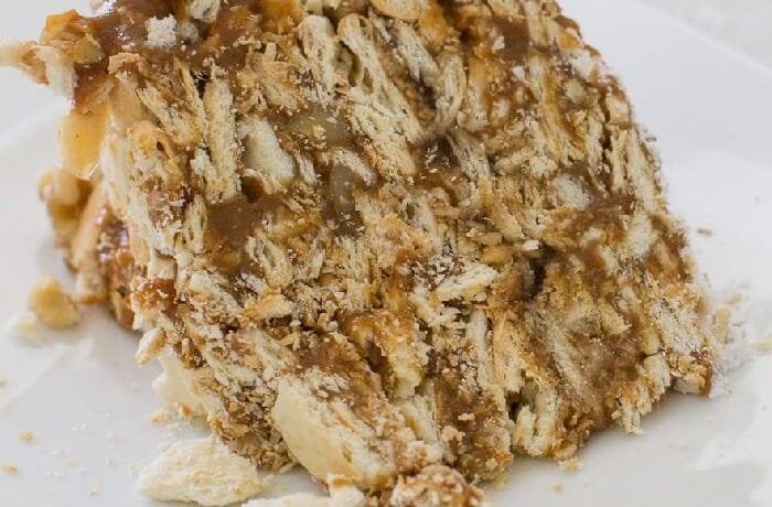 Slice of Chilean soda cracker cake layered with manjar and jam, a no-bake dessert dusted with powdered sugar