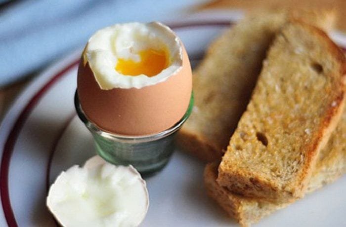 Chilean soft-boiled eggs in egg cups with toast and runny yolks