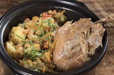 Chilean picante de conejo on a plate with boiled potatoes and cilantro