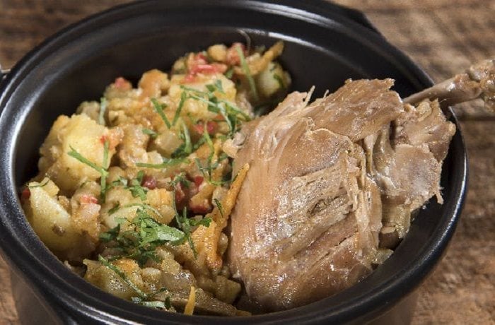 Chilean picante de conejo on a plate with boiled potatoes and cilantro