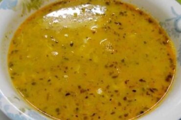 Steaming bowl of Chilean toasted flour soup with threads of egg white and a dusting of red merken on the surface