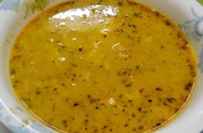 Steaming bowl of Chilean toasted flour soup with threads of egg white and a dusting of red merken on the surface
