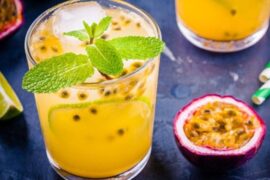 Refreshing tropical gin and passion fruit cocktail in a tall glass, garnished with a pineapple slice and passion fruit seeds.