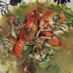 Chilean vega mud shrimp chowder served in a deep bowl, with shrimp and egg in the broth.