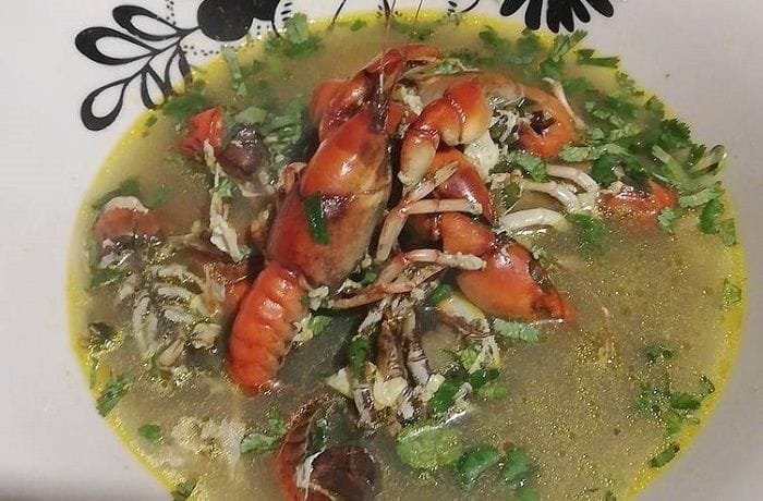 Chilean vega mud shrimp chowder served in a deep bowl, with shrimp and egg in the broth.