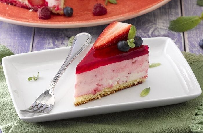 Chilean yogurt and sponge cake with a bright red gelatin top and fresh strawberries inside