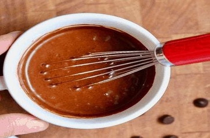 Chocolate-colored mug cake batter being mixed in a bowl.