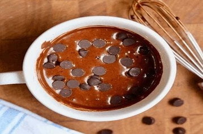 Chocolate chips being added on top of the mug cake batter.