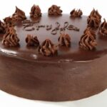Chocolate truffle cake covered in ganache and decorated with sprinkles