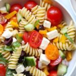 Cold spiral pasta salad with spinach, cherry tomatoes, and mozzarella