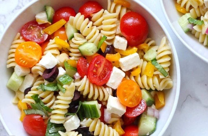 Cold spiral pasta salad with spinach, cherry tomatoes, and mozzarella