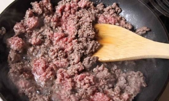 Cooked ground beef Ground beef cooking in a skillet with spices, releasing its natural juices.