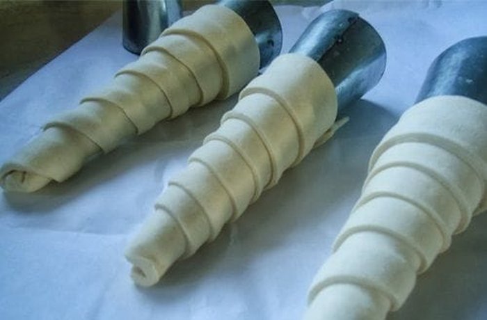 Strips of dough wrapped around conical molds, ready to go into the oven
