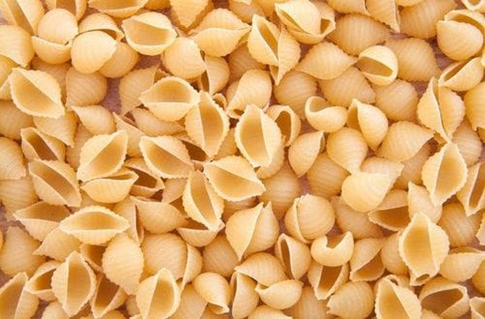 Dry shell-shaped pasta (conchiglie) in a bowl, ready for boiling.