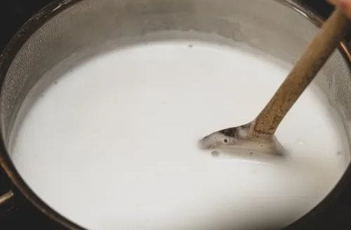 Heating milk for cheese sauce Milk heating in a small pot, the first step in making the creamy cheese sauce.