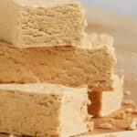 Homemade Argentine mantecol, a marbled peanut nougat cut into cubes on a wooden board