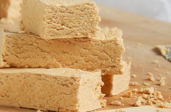 Homemade Argentine mantecol, a marbled peanut nougat cut into cubes on a wooden board