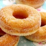 Homemade donuts with vanilla glaze and colored sprinkles on a cooling rack