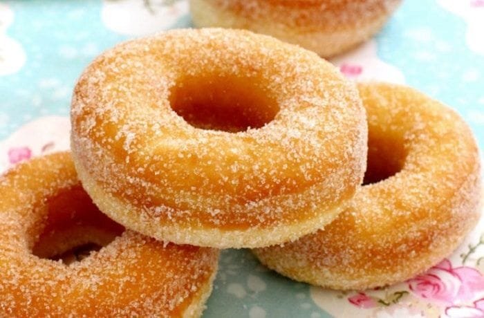 Homemade donuts with vanilla glaze and colored sprinkles on a cooling rack