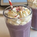Homemade purple berry milkshake inspired by the Grimace Shake, topped with whipped cream
