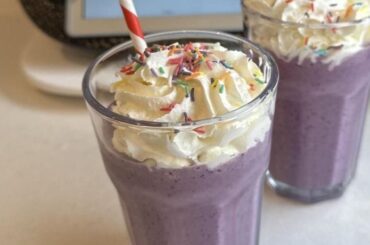 Homemade purple berry milkshake inspired by the Grimace Shake, topped with whipped cream