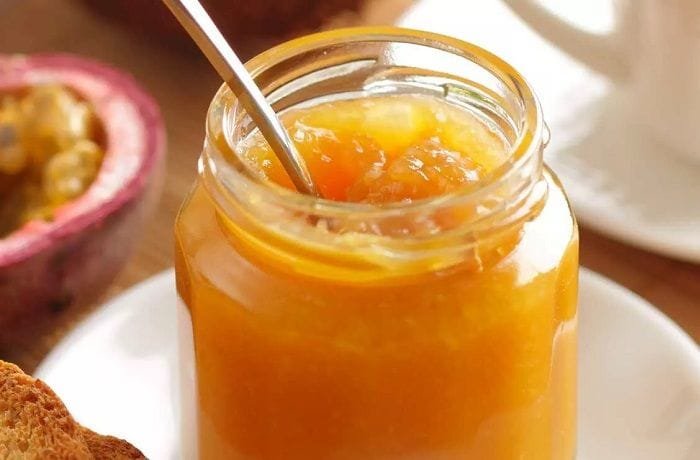 Homemade passion fruit jam in a glass jar with a bright, glossy texture