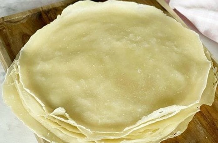 Thin homemade spring roll wrappers stacked on a rack