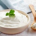 Homemade crema acida in a white ceramic bowl with a pinch of merken and pepper