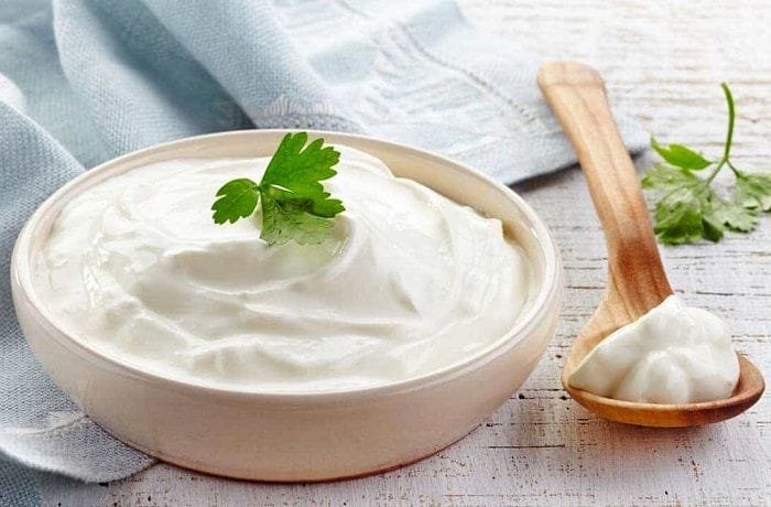 Homemade crema acida in a white ceramic bowl with a pinch of merken and pepper