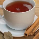 Cup of golden bay leaf and cinnamon infusion known as Japanese tea, with a lemon wedge