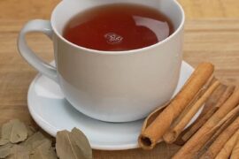 Cup of golden bay leaf and cinnamon infusion known as Japanese tea, with a lemon wedge