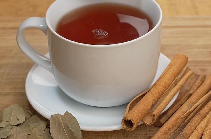 Cup of golden bay leaf and cinnamon infusion known as Japanese tea, with a lemon wedge