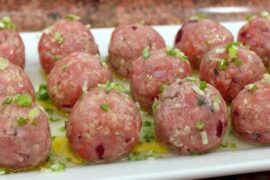 Kibbeh nayyeh spread on a plate, garnished with fresh mint, olive oil, and lemon slices.