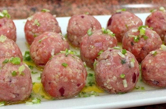 Kibbeh nayyeh spread on a plate, garnished with fresh mint, olive oil, and lemon slices.