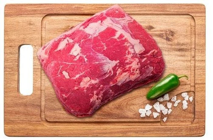 Whole cut of beef sirloin on a board, ready to be seared in a hot pan before roasting