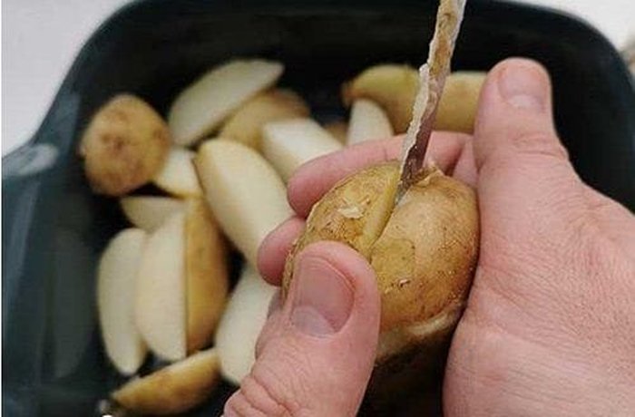 Potato wedges tossed in olive oil, garlic, and herbs in a glass bowl