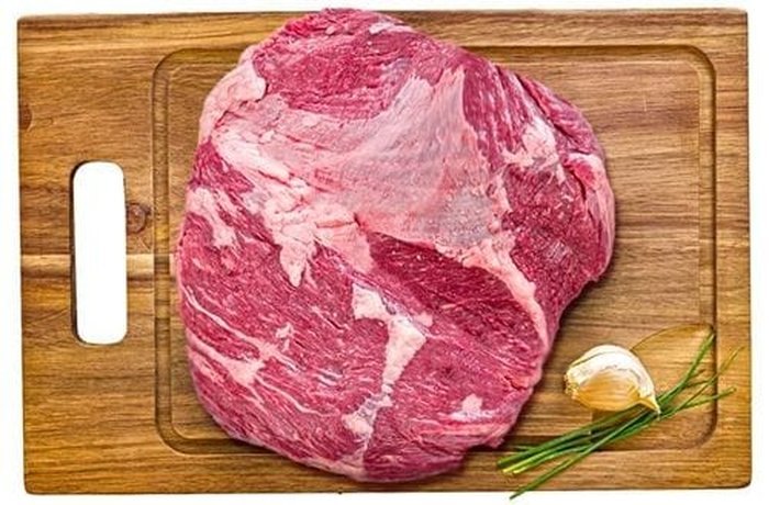 The raw beef cut showing its characteristic layer of white fat on the outer face.