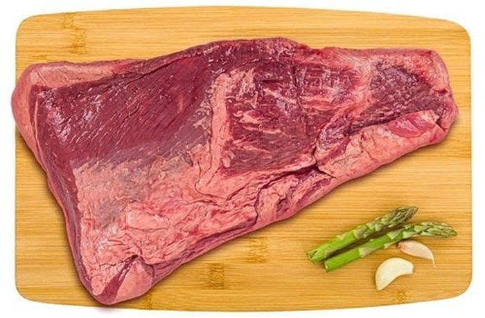 A raw tapapecho beef cut with its fat cap, seasoned and ready to be seared.