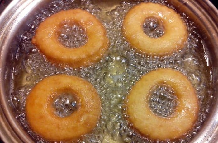 Roscas submerged in bubbling hot oil, frying to a perfect golden color.