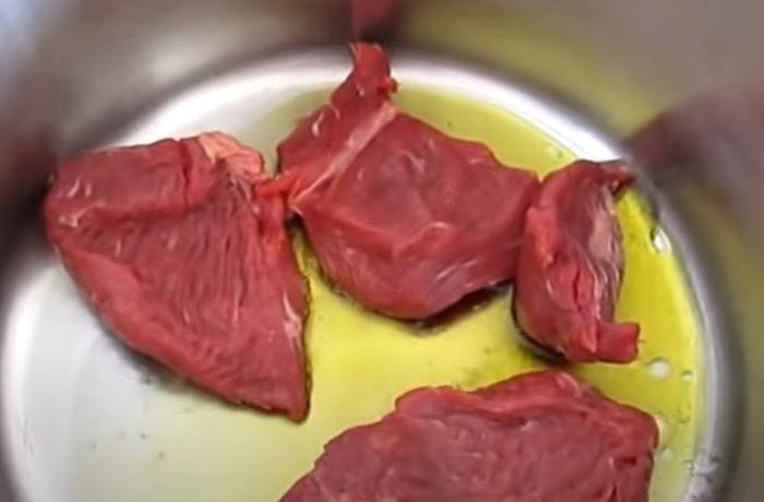 Beef pieces browning in a pot with oil to seal in the juices for carne al jugo