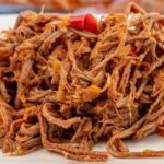 Shredded beef ropa vieja in tomato hogao sauce served with white rice