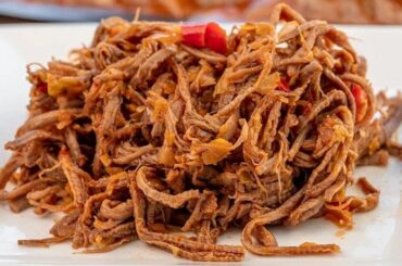 Shredded beef ropa vieja in tomato hogao sauce served with white rice