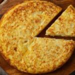 Golden Spanish potato omelette, tortilla de papas, sliced on a plate
