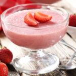 Pale pink strawberry yogurt gelatin in a glass decorated with fresh strawberries
