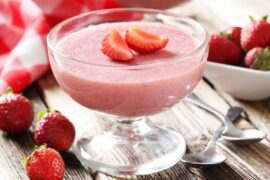 Pale pink strawberry yogurt gelatin in a glass decorated with fresh strawberries